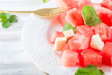 Salata karpuz peynir ve nane beyaz kase Beyaz ahşap masa üstünde ve çatal ile adet üzerinden. Kopya alanı.