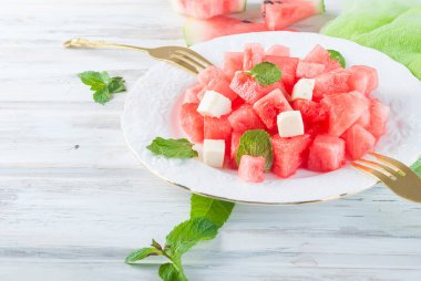 Salata karpuz peynir ve nane beyaz kase Beyaz ahşap masa üstünde ve çatal ile adet üzerinden. Kopya alanı.