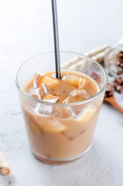 coffee ice in glass and coffee beans in wooden spoon on a gray  table, top view, copy space