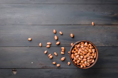 Eski koyu ahşap arka plan seçici odak üzerinde kahverengi bir seramik kase çiğ soyulmuş fıstık 