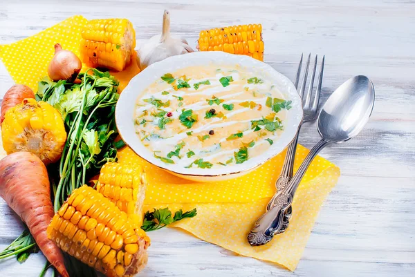 Ev yapımı Mısır krem çorbası ekşi krema, beyaz bir tabak ve dilim kızarmış Mısır koçanı Beyaz ahşap bir masa üzerinde otlar. üstten görünüm, kopya alanı 