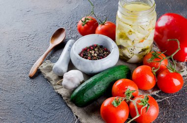 Marine edilmiş baharatlı beyaz bir kavanoz, domates ve salatalık salatası için. Karanlık bir arka plan üzerinde. Metniniz için kopya alanı. 