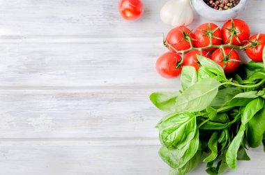 olgun domates, çok Yeşil fesleğen ve sarımsak, tuz ve baharat beyaz eski rustik ahşap zemin üzerinde bir taş harç içinde. Üstten görünüm, kopya alanı. 