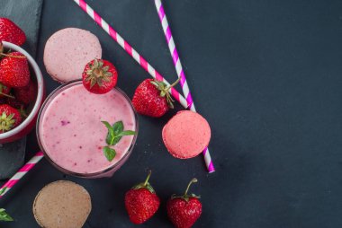 Bir cam yakın çekim ve masanın üzerine taze çilek kase çilek ve yaban mersini smoothies yenileniyor.