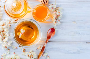 Çaydanlık ve şube akasya eski rustik beyaz ahşap masa üzerinde demlenmiş akasya çiçekleri bal ile şifa bitki çayı.