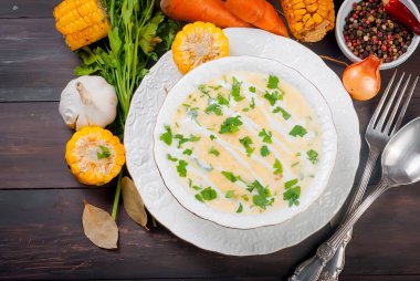 Ev yapımı Mısır krem çorbası ekşi krema, beyaz bir tabak ve dilim kızarmış Mısır koçanı eski koyu ahşap masa üzerinde otlar. üstten görünüm, kopya alanı