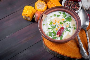 Ev yapımı Mısır krem çorbası ekşi krema, karanlık bir seramik tabak ve dilim kızarmış Mısır koçanı eski koyu ahşap masa üzerinde otlar. üstten görünüm, kopya alanı 