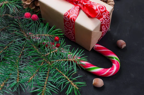 装饰背景与冷杉树枝 冻浆果干果 糖果棒 和礼物在黑桌上 圣诞贺卡节日的概念 复制空间 顶部视图 — 图库照片