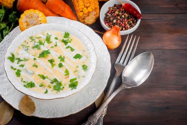 Ev yapımı Mısır krem çorbası ekşi krema, beyaz bir tabak ve dilim kızarmış Mısır koçanı eski koyu ahşap masa üzerinde otlar. üstten görünüm, kopya alanı