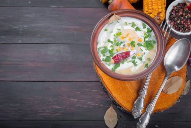 Ev yapımı Mısır krem çorbası ekşi krema, karanlık bir seramik tabak ve dilim kızarmış Mısır koçanı eski koyu ahşap masa üzerinde otlar. üstten görünüm, kopya alanı 