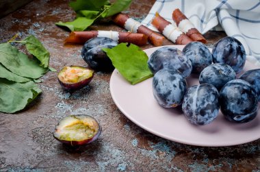 Bir seramik tabak bir erik taze mor Erik yarıya ve parlak meyve hamuru koyu kahverengi rustik arka plan üzerinde seçici odak, kopya alanı parlıyor 