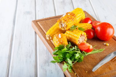 Lezzetli Barbecued Mısır koçanı otlar, sebzeler ve tuz bir tahta ve bir beyaz ahşap masa