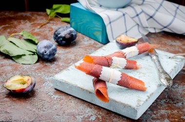 Kase taze mor Erik bir çömlek içinde mavi ve masanın üzerine dağılmış, erik meyve deri ve kuru cips şeklinde rulolar üzerinde koyu arka plan. Detoks kavramı. Sağlıklı gıda, meyve inanılmaz şeker. seçici odak, kopya alanı 