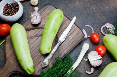 Genç bahar kabağı, domates, bitki ve baharatlar yukarıdan siyah arka planda. Kızartma için taze bahar sebzeleri. Bedava metin alanı olan arkaplan düzeni. Üst Manzara. Boşluğu kopyala.