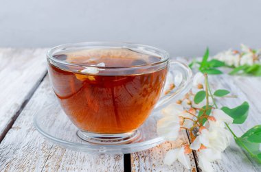 Çaydanlık ve şube akasya eski rustik ahşap masa üzerinde demlenmiş akasya çiçekleri bal ile şifa bitki çayı. 