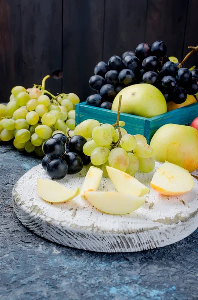 新鮮な黄色いりんご 白と青のブドウ テーブル スライス フルーツ フルーツの革に散在して 暗い背景にロールします デトックス概念 健康食品 素晴らしい果物お菓子します — ストック写真
