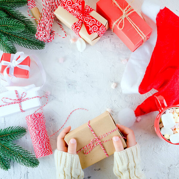 child is holding  Christmas gift box tied with a red ribbon, red cup cocoa with  marshmallow  on the white background. Christmas card Holiday Concept, copy space