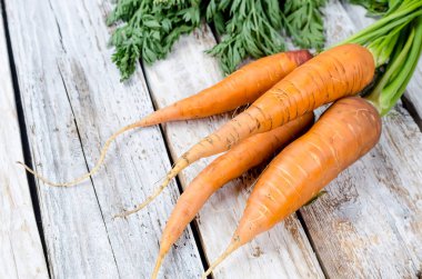 Rustik beyaz ahşap zemin üzerine yeşil yaprakları ile taze havuç demet. Sebze. Gıda. Kopya alanı, üstten görünüm