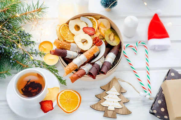warming Tea and round wooden gift box with Many variety of dry  fruit chips and fruit leather rolls on white background in the winter Christmas day, Holidays concept. Detox concept. Healthy food, Fruits amazing candy. selective focus,