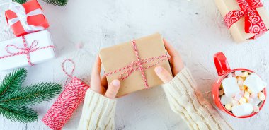 Çocuk Noel tutan hediye kutusu bağlı ile hatmi beyaz zemin üzerine kırmızı kurdele, kırmızı Kupası kakaolu. Noel kartı tatil kavramı, kopya alanı