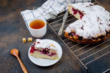 Kiraz veya erik Pasta krema şeker, rustik koyu arka plan üzerinde çay ile serpilir yakın çekim, yukarıdan görünüm 