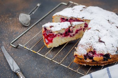 Kiraz veya erik Pasta krema şeker, rustik koyu arka plan üzerinde çay ile serpilir yakın çekim, yukarıdan görünüm 
