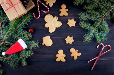 Birçok gingerbread ile Noel kompozisyon, koyu ahşap masa köknar branhes ve hediye kutusunda. Arka plan, üstten görünüm, kopyalama spase tatil kavramı