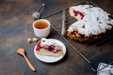 Kiraz veya erik Pasta krema şeker, rustik koyu arka plan üzerinde çay ile serpilir yakın çekim, yukarıdan görünüm 
