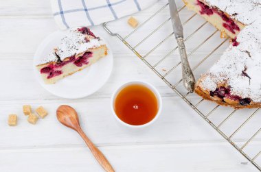 Kiraz veya erik pasta serpilir ile krema şeker, beyaz çay ahşap panoları, yakın çekim, görüntülemek yukarıdan 