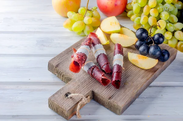 新鮮な黄色いりんご 白と青のブドウ テーブル スライス フルーツ フルーツの革に散在して白い木製のテーブルのロールします デトックス概念 健康食品 素晴らしい果物お菓子します 選択と集中 — ストック写真