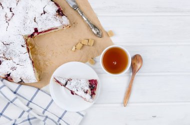 Kiraz veya erik pasta serpilir ile krema şeker, beyaz çay ahşap panoları, yakın çekim, görüntülemek yukarıdan 