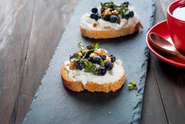Bir fincan sert kahve ve yumuşak ricotta peyniri, çilek ve beyaz ahşap masa, doğal ışık, sağlık gıda kavramı günü kahvaltıda bal ile iki sandviç