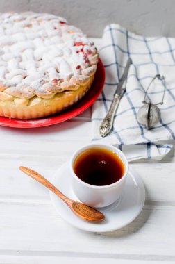 Lezzetli ev yapımı kiraz pasta plaka whits fincan beyaz eski ahşap masa üzerinde çay şekeri krema ile silkeledi. Vişneli pasta serisi yapma, 