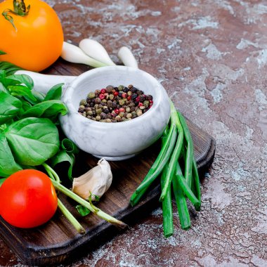 Olgun kırmızı ve sarı domates, yeşil soğan ve fesleğen, sarımsak, tuz ve baharat karanlık bir taş zemin üzerine. Üstten görünüm, kopya alanı. 