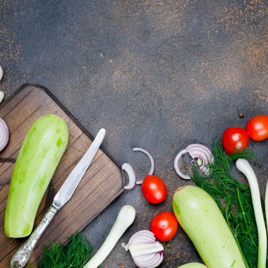 Genç bahar kabağı, domates, bitki ve baharatlar yukarıdan siyah arka planda. Kızartma için taze bahar sebzeleri. Bedava metin alanı olan arkaplan düzeni. Üst Manzara. Boşluğu kopyala.