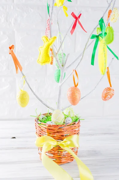 colorful easter felt toys and eggs on tree branches in pot as easter decorations close up, holiday concept, copy space