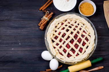 Bir bardak çiğ vişneli pasta kek - un, yumurta, kiraz, kahverengi şeker, cinamon karanlık eski ahşap masa üzerinde yapmak için formu ve malzemeler yuvarlak. Vişneli pasta serisi yapma, 