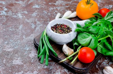 Olgun kırmızı ve sarı domates, yeşil soğan ve fesleğen, sarımsak, tuz ve baharat karanlık bir taş zemin üzerine. Üstten görünüm, kopya alanı. 