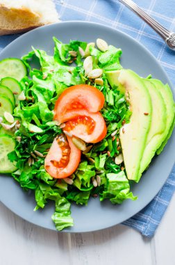  Taze yeşil salata salatalık, marul, avokado ve domates ve cam su beyaz ahşap bir masa üzerinde. Gıda sağlıklı yaşam konsepti. Düz yatıyordu. Metin için yer kopyalayın