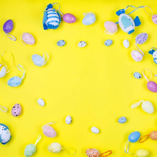 various decorative eggs laid out on a yellow background, top view, flat lay, holiday background, copy space