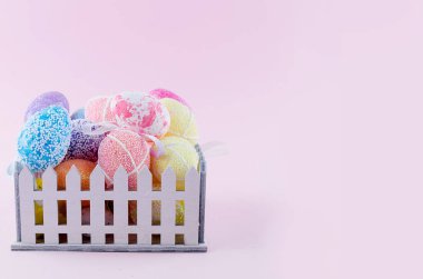 sepet hafif pembe bir arka plan üzerinde renkli dekoratif yumurtalar. tebrik kartı Paskalya, üstten görünüm, düz lay, tatil arka plan, kopyalama alanı