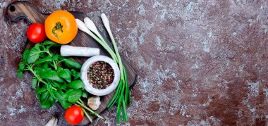 Olgun kırmızı ve sarı domates, yeşil soğan ve fesleğen, sarımsak, tuz ve baharat karanlık bir taş zemin üzerine. Üstten görünüm, kopya alanı. 