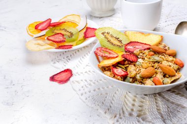 Taze gevrek, badem, fıstık, tohum ve çeşitli meyve çipleri ve pastil şeker Beyaz ahşap arka planda, seçici odak, beyaz bir tabak içinde ile müsli sağlıklı gıda kavramı, kopya alanı Detoks