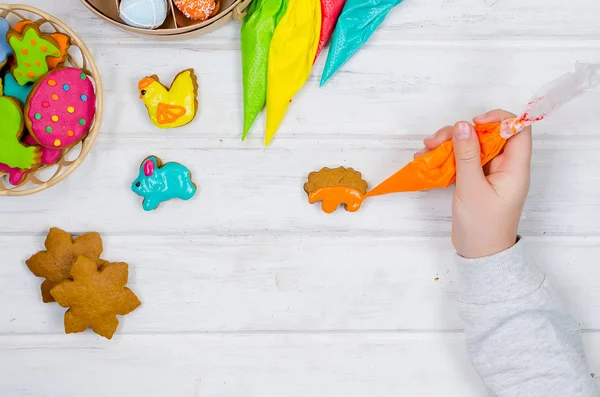 Girl decorating gingerbread with icing for Easter — Stock Photo, Image