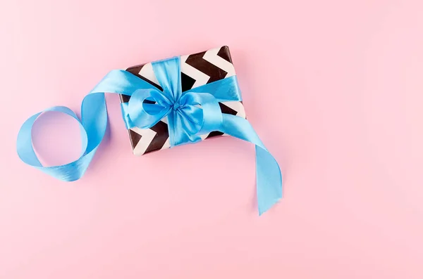 Gift with blue ribbon on a pink background — Stock Photo, Image