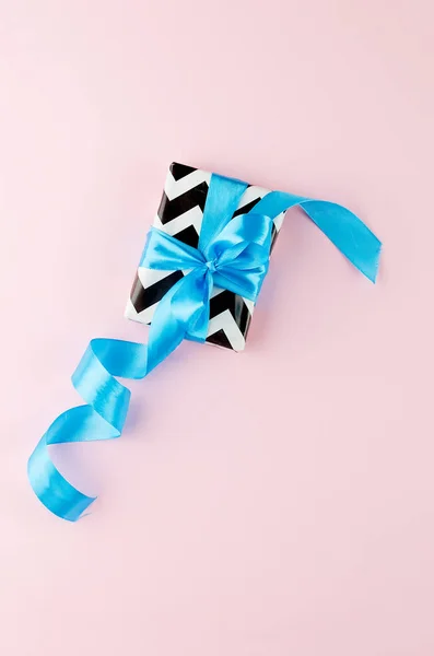 Gift with blue ribbon on a pink background — Stock Photo, Image