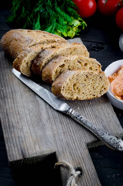 Темный багет, нарезанный на кусочки и пряное масло — стоковое фото