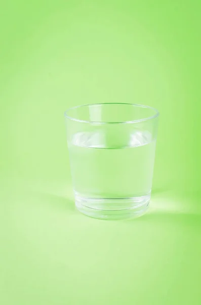 Стакан воды на зеленом фоне — стоковое фото