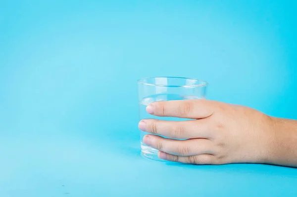 Vidro de água na mão em azul — Fotografia de Stock