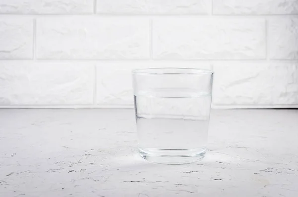 Стакан воды на светлом бетонном столе — стоковое фото